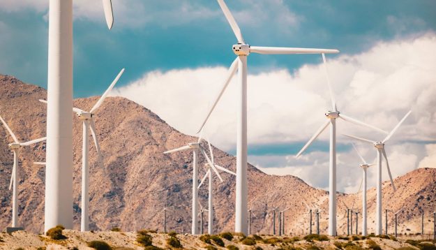 vertical low angle shot lot windmills field surrounded by high rocky mountains
