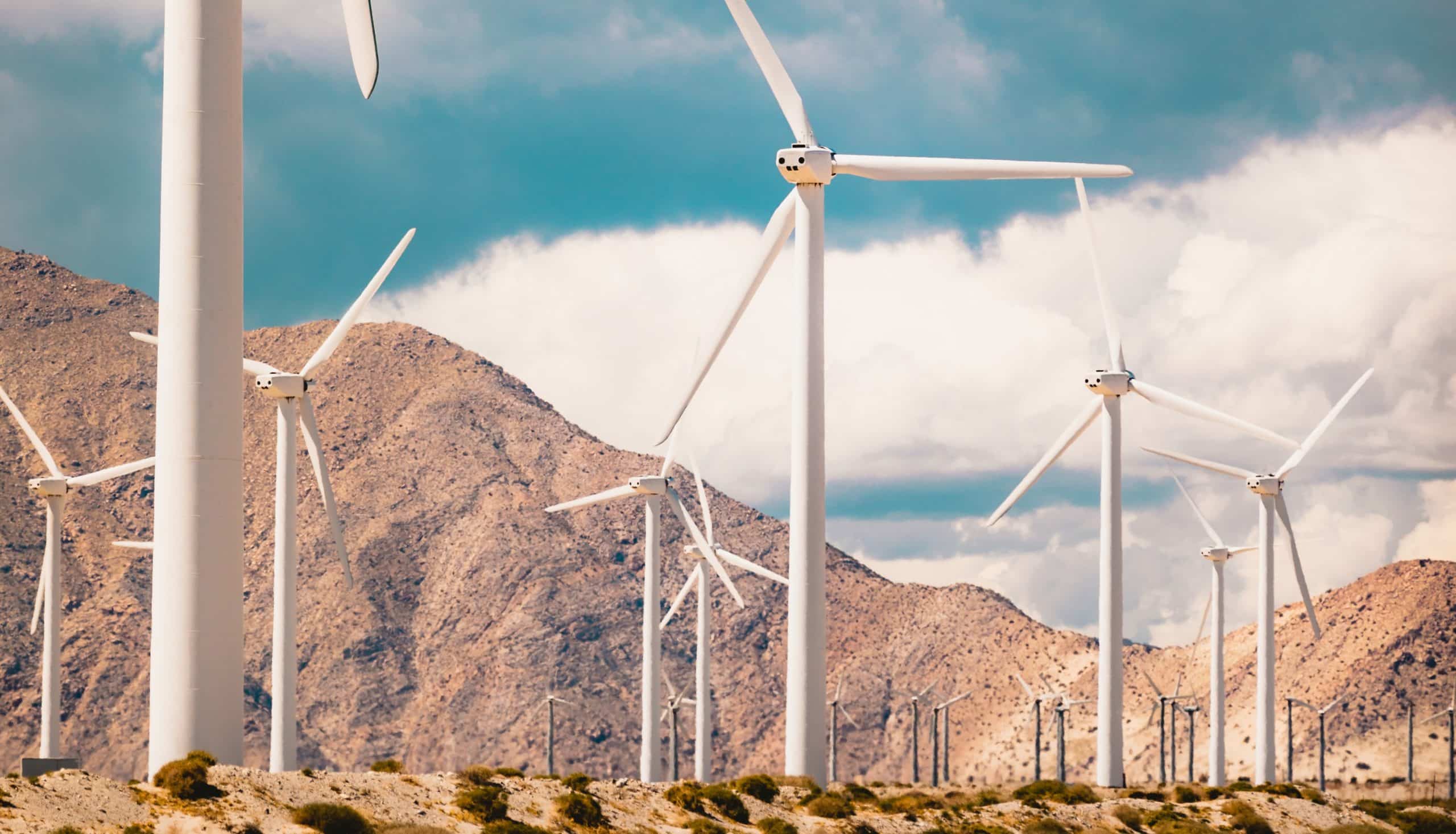 vertical low angle shot lot windmills field surrounded by high rocky mountains